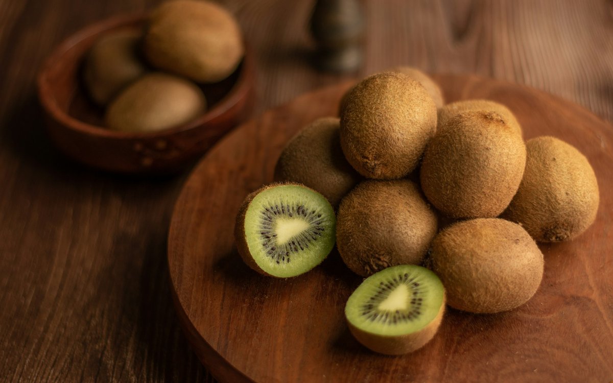 Kiwis entiers et coupés sur un plateau en bois