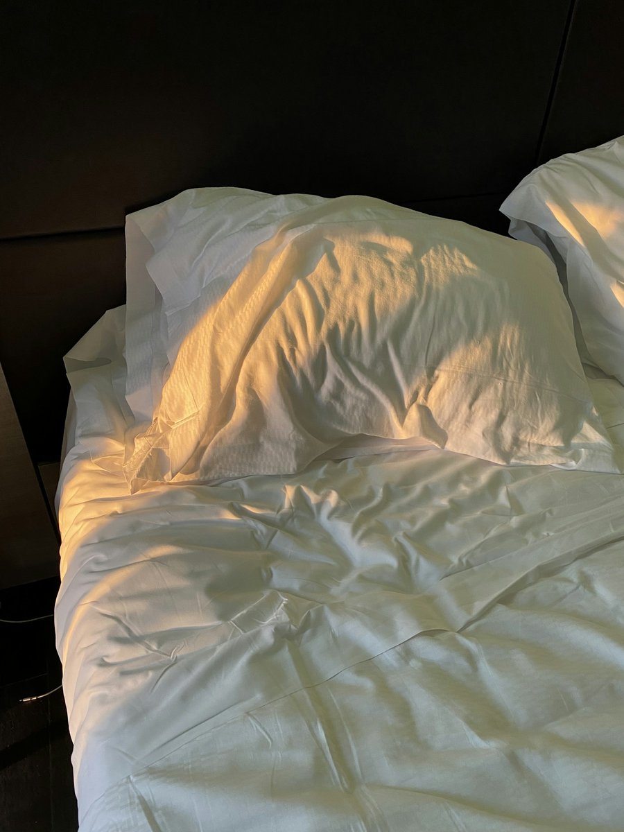 Oreiller et couette blancs baignés d'une lumière chaude de fin de journée