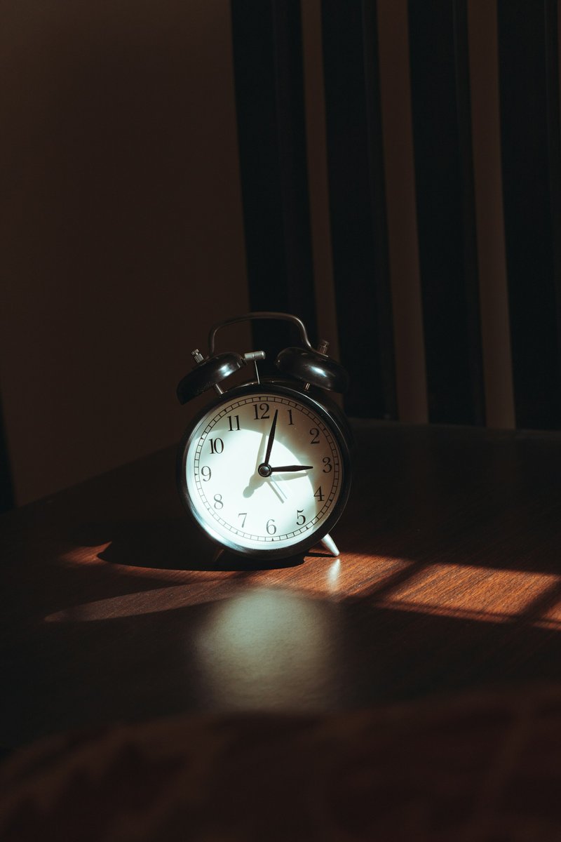 Réveil posé sur une table de nuit dans la pénombre de la chambre