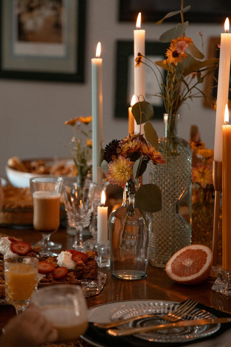 Table du soir dressée avec des bougies allumées et un bouquet de fleurs séchées